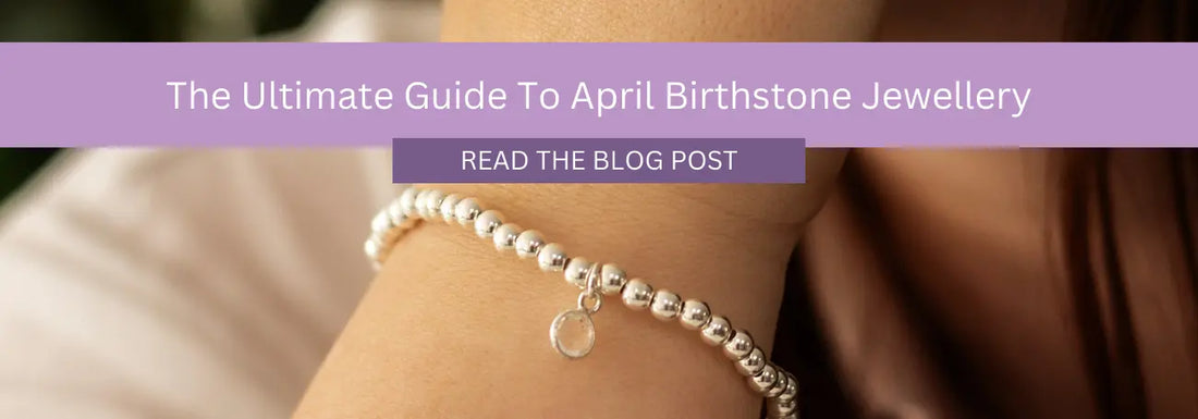 A person's wrist adorned with a silver beaded bracelet featuring a small circular charm is shown in close-up view. Overlaid text reads, "The Ultimate Guide To April Birthstone Jewellery" and "Read the Blog Post" on a purple banner.