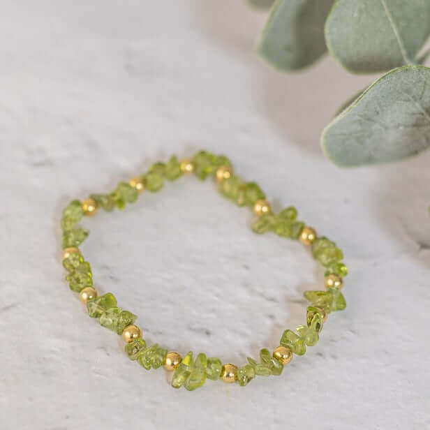 Peridot birthstone bracelet made with crystal chips and gold beads, gold, oval flat lay
