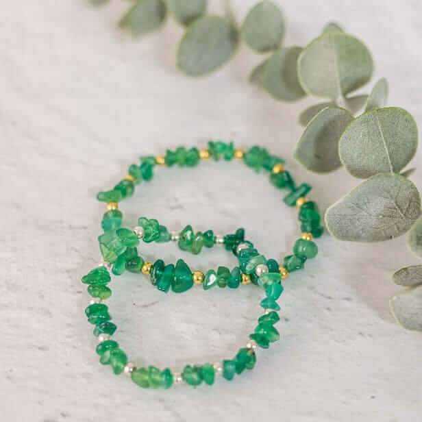 Two green agate crystal bracelets with silver and gold bead accents laid flat – vibrant gemstone chip stacking bracelets for grounding and balance.