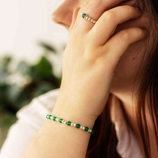 Woman wearing a green gemstone bracelet and matching ring – a dainty handmade crystal jewellery set.