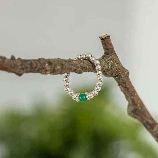 Handmade sterling silver beaded ring with green agate centre – calming stretch gemstone ring displayed on a natural twig.