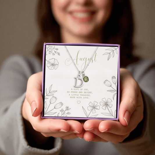 Sterling silver initial and peridot August birthstone necklace presented in a purple gift box with floral card reading “A gift of joy, so fresh and bright”