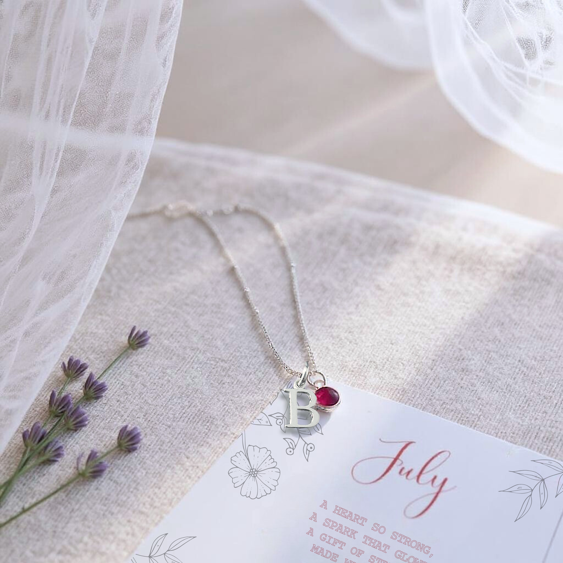 July birthstone and letter necklace shown resting on july birthstone message card. This Ruby birthstone necklace is the perfect personalised gift for a loved one.