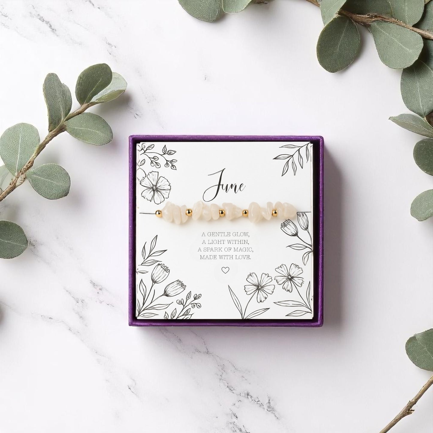 Handmade moonstone June birthstone bracelet with crystal chip beads and gold accents, displayed on a floral message card in a purple gift box. A calming gemstone stretch bracelet made with love, perfect as a meaningful gift.