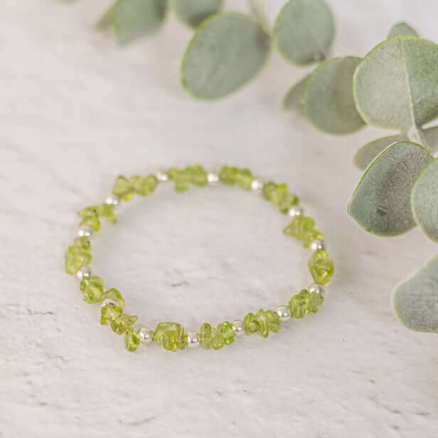 Handmade peridot chip crystal bracelet in sterling silver, laid flat on white background