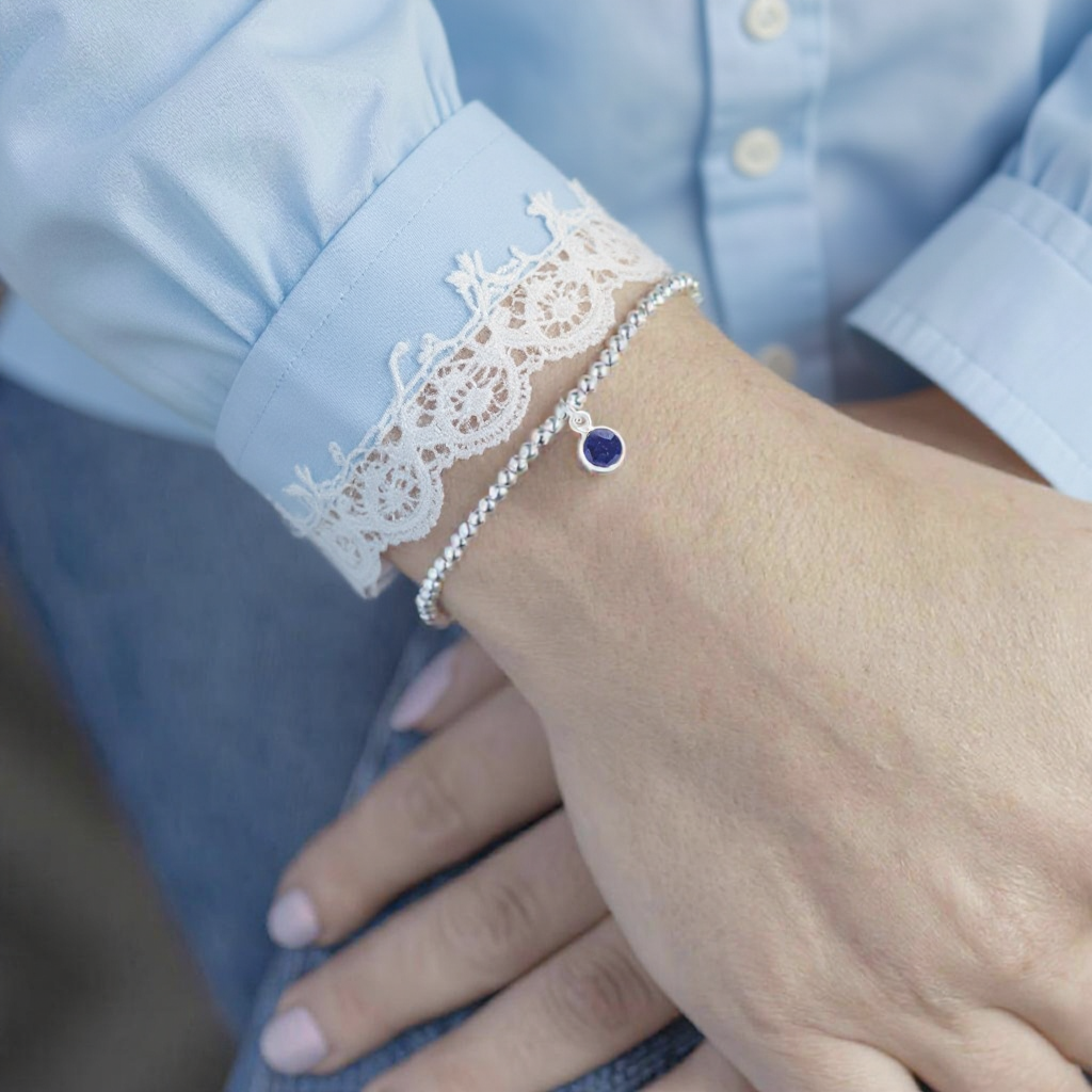 a september birthstone bracelet, featuring a sapphire charm on a stretchy sterling silver bead bracelet. perfect gift for daughter from daddy