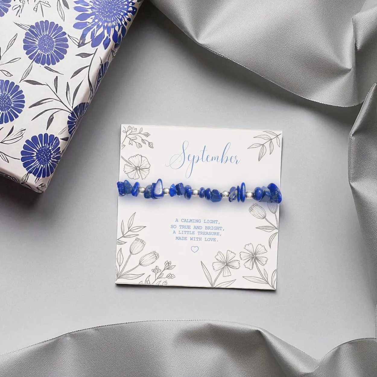 a dark blue crystal bracelet, stretch design, silver spacer beads, wrapped around a september birthday gift card, lapis lazuli stone bracelet