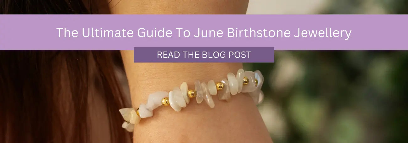  Close-up of a woman's wrist wearing a bracelet made of light-colored stones and small gold beads. A purple banner across the top reads, "The Ultimate Guide To June Birthstone Jewellery," with a button below labeled "Read the Blog Post."