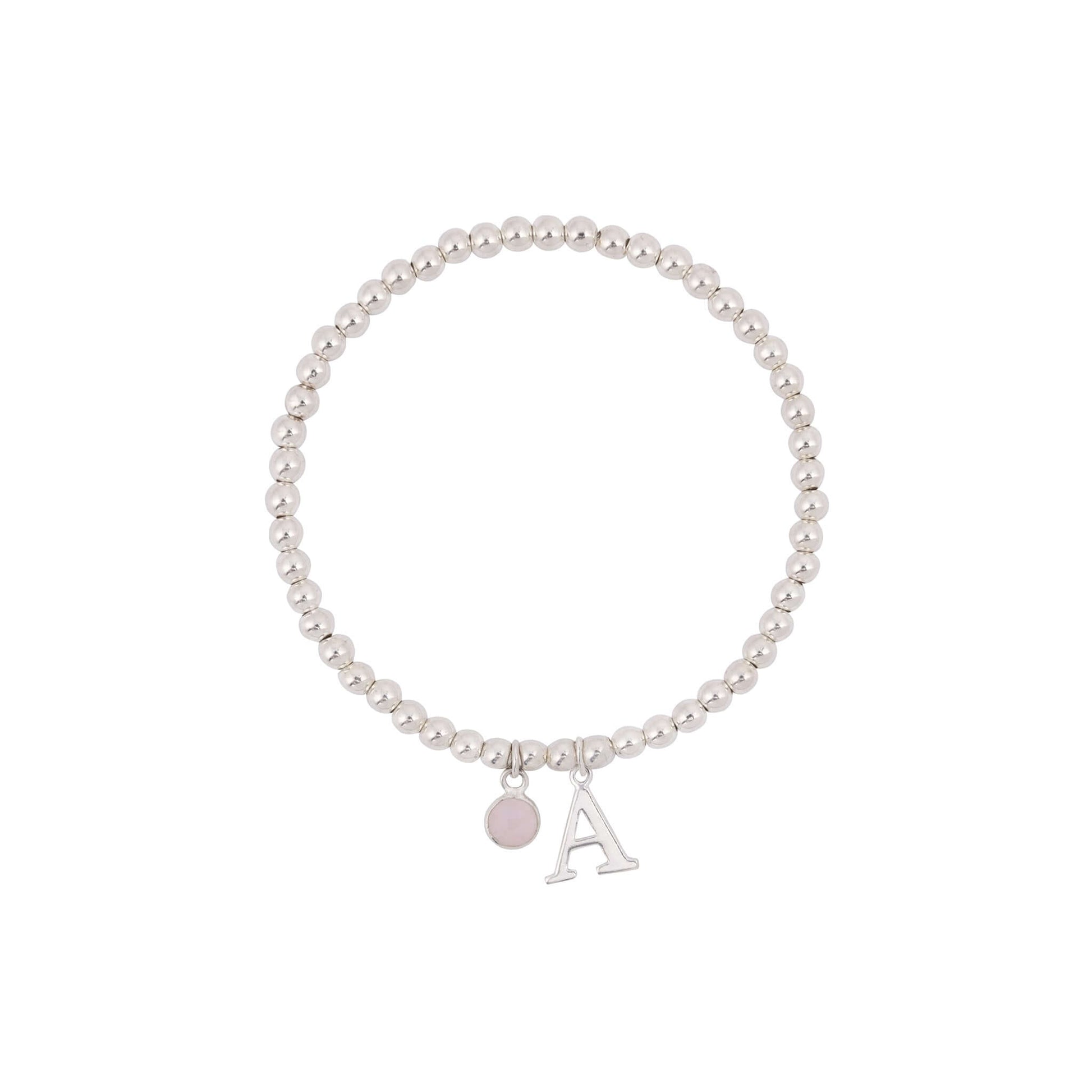 A Made Here with Love Initial Letter & Birthstone Charm Bracelet with sterling silver beads and two dangling charms: a small circular pink charm and a larger letter "A" charm. The bracelet is arranged in a circular shape and appears minimalistic and elegant. The beads have a polished, reflective finish, perfect as an amethyst birthstone bracelet.