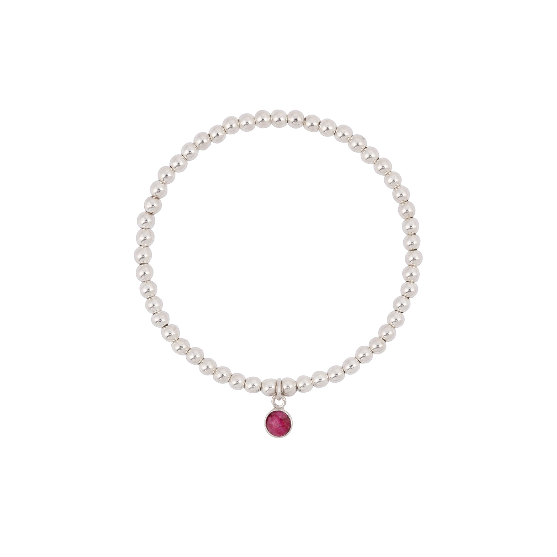 A beaded silver bracelet with a tiny ruby birthstone charm hanging from the center. The Made Here with Love July Birthstone Bracelet is made of uniform sterling silver beads and has a simple, elegant design. The ruby charm adds a subtle pop of color to the overall minimalistic look.