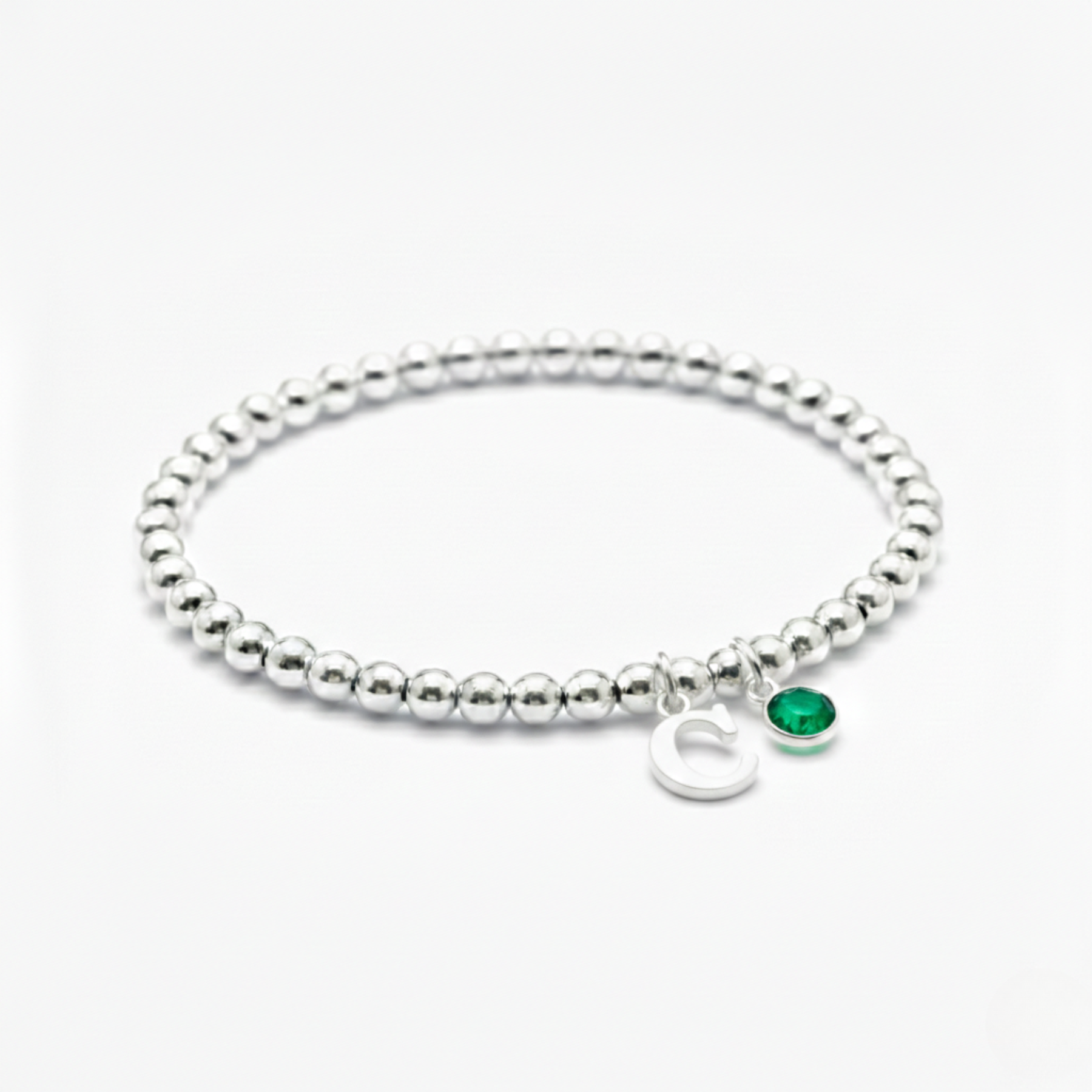 May birthstone bracelet with emerald charm and personalised initial detail