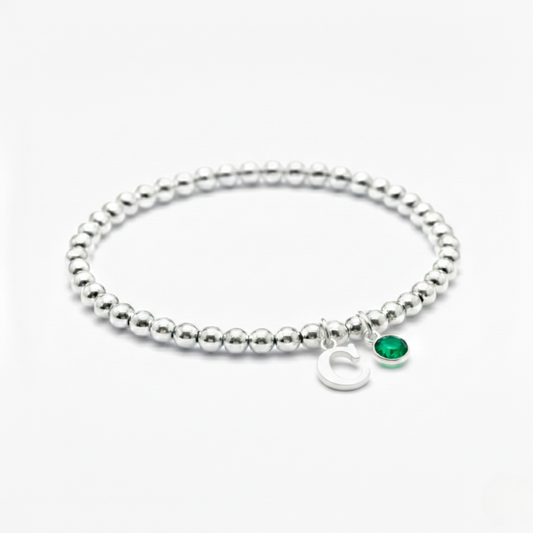 May birthstone bracelet with emerald charm and personalised initial detail