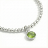 August birthstone stretch bead bracelet with peridot charm, featuring sterling silver beads and green gemstone.