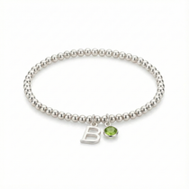 Birthstone bracelet with peridot charm on a sterling silver stretch bracelet, styled as a personalised gift.