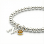November birthstone citrine bracelet with initial letter charm on a sterling silver stretch bracelet.