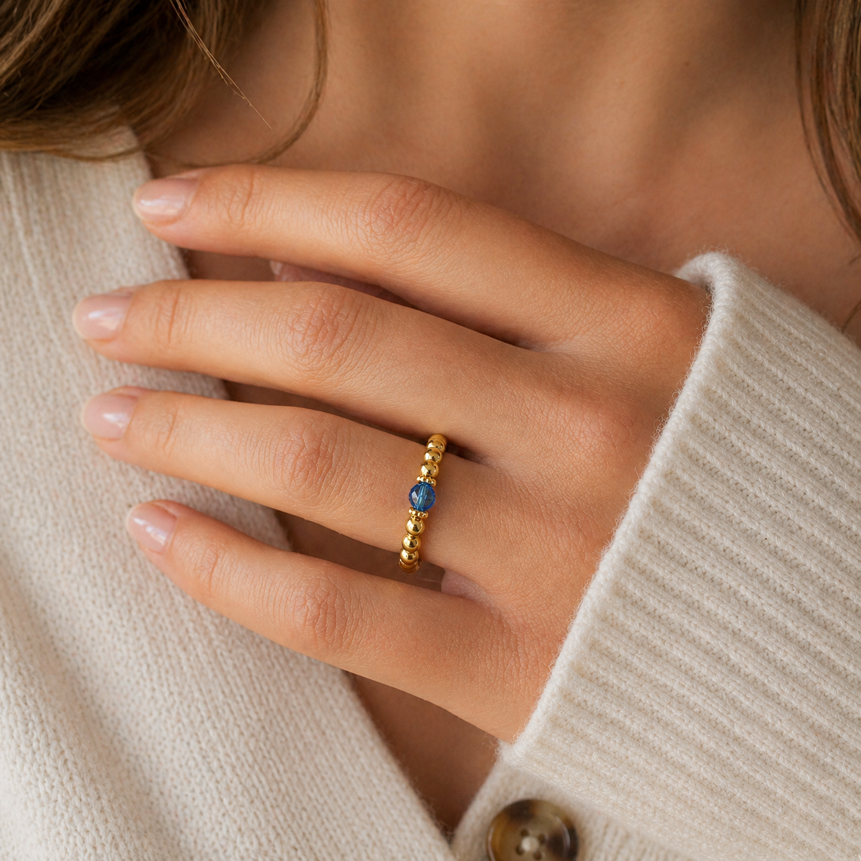 close up of a capri blue crystal ring with a faceted blue gemstone set on a gold filled bead ring.