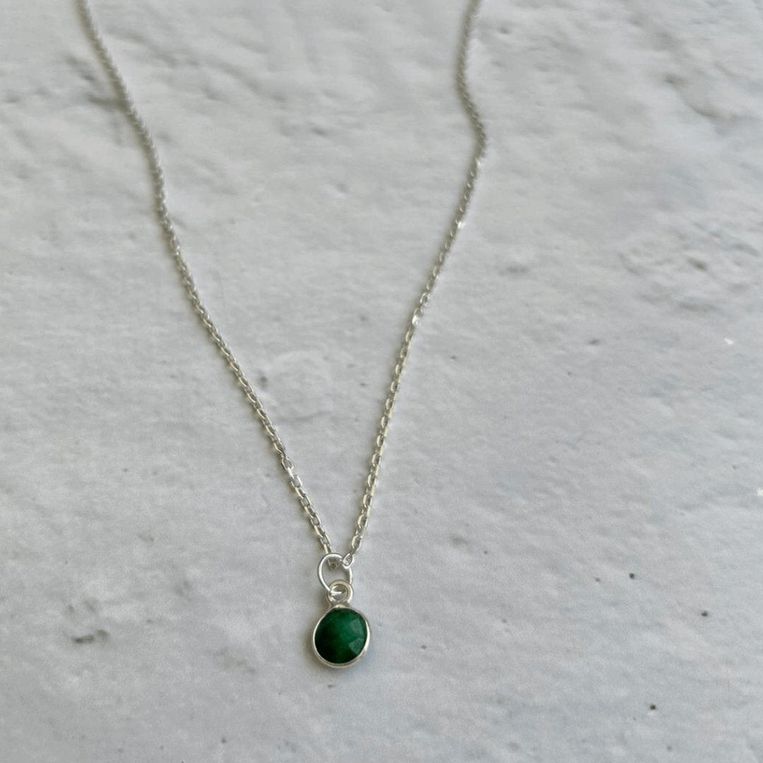 Close-up of sterling silver birthstone necklace with emerald green charm – available on trace or satellite chain.