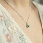 Emerald May birthstone necklace worn on chain, featuring a vibrant green gemstone charm.