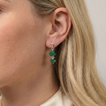 Emerald coloured drop earrings worn, featuring deep green gemstone beads.