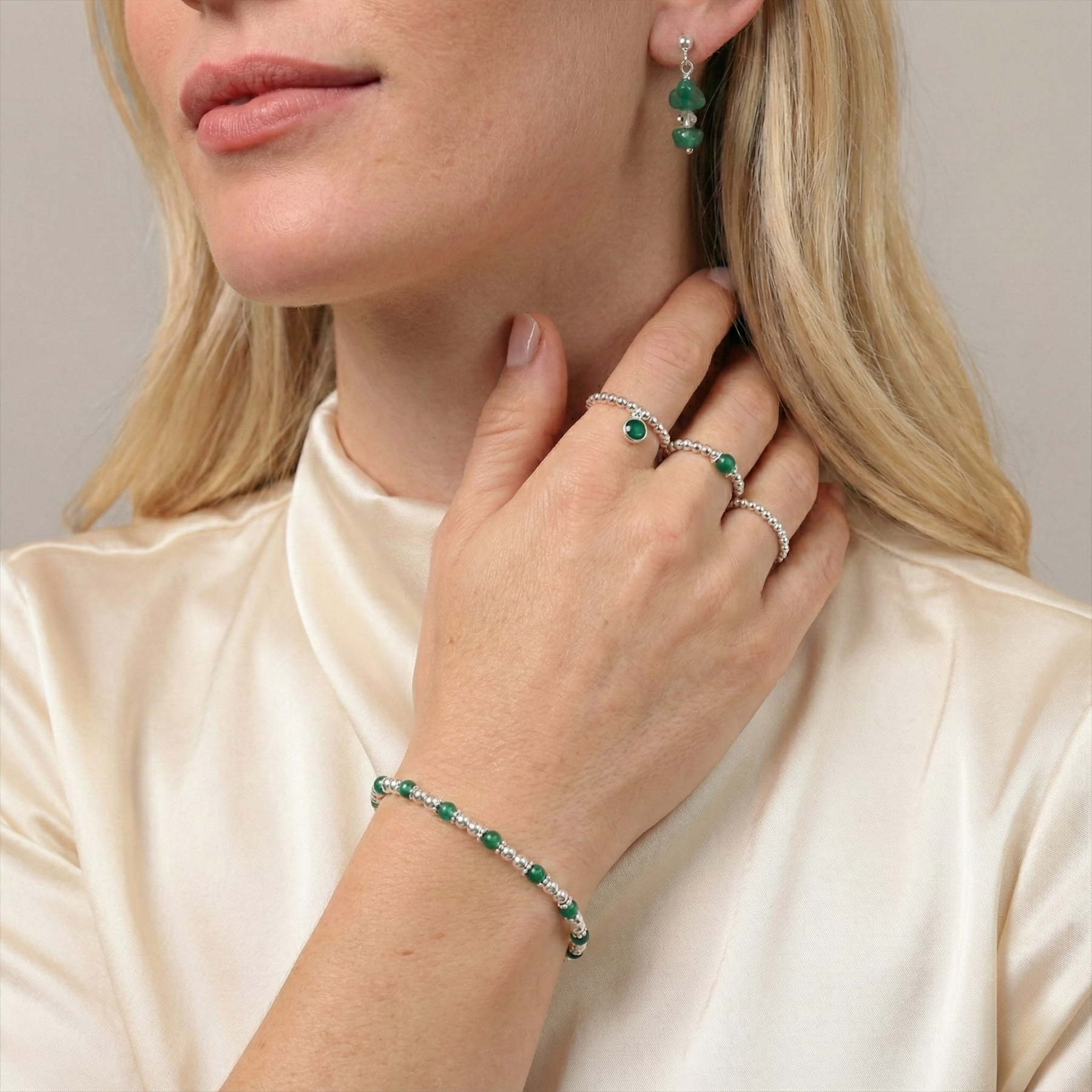Emerald coloured jewellery worn together, featuring green gemstone earrings and coordinating pieces.