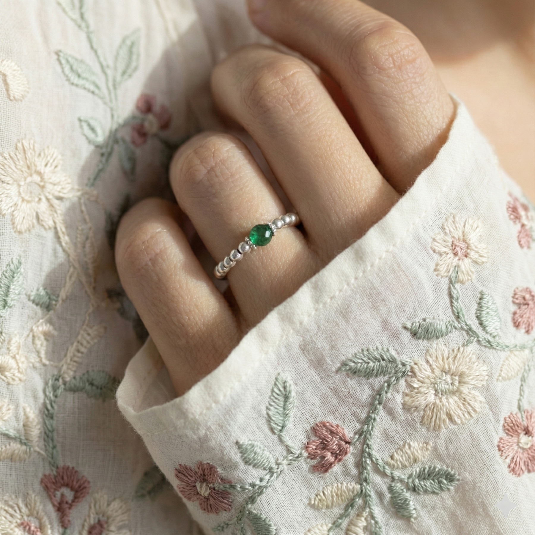 Emerald green gemstone bead ring with sterling silver stretch beads, worn on finger.