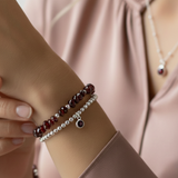 January garnet gemstone stacking jewellery set worn on wrist, featuring red garnet bracelet layered with sterling silver bead bracelets.