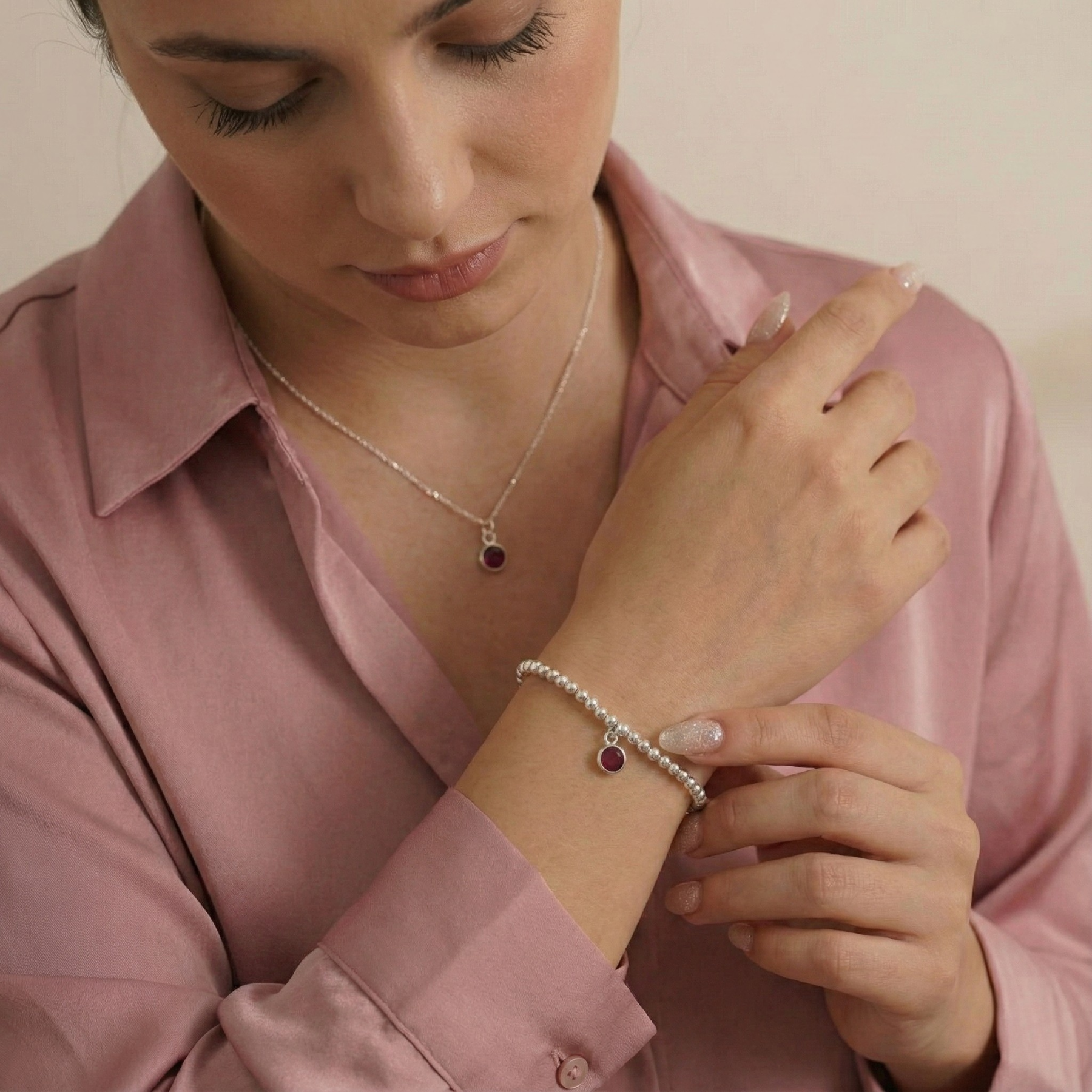 Sterling silver garnet jewellery worn together, featuring a garnet charm bracelet and matching necklace.