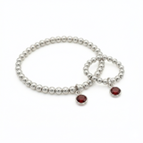 January garnet birthstone jewellery set featuring a sterling silver charm bracelet with deep red garnet details.