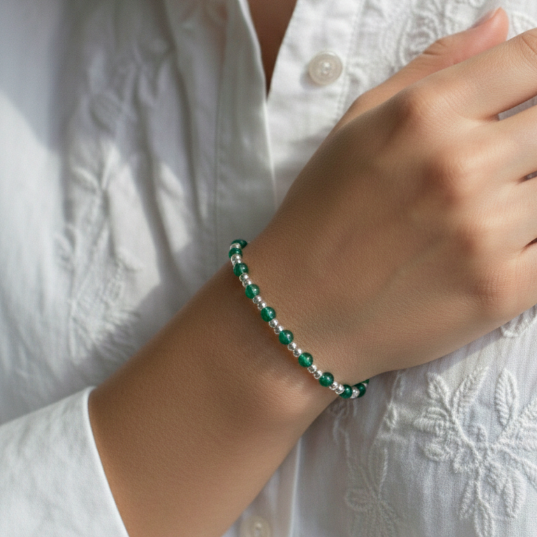 Green agate bead bracelet worn on wrist, featuring green gemstones and sterling silver stretch bead design.