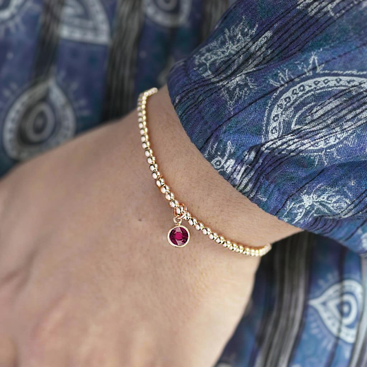 Gold vermeil stretch bead bracelet with july ruby birthstone charm. Perfect for gifting to your loved ones. 