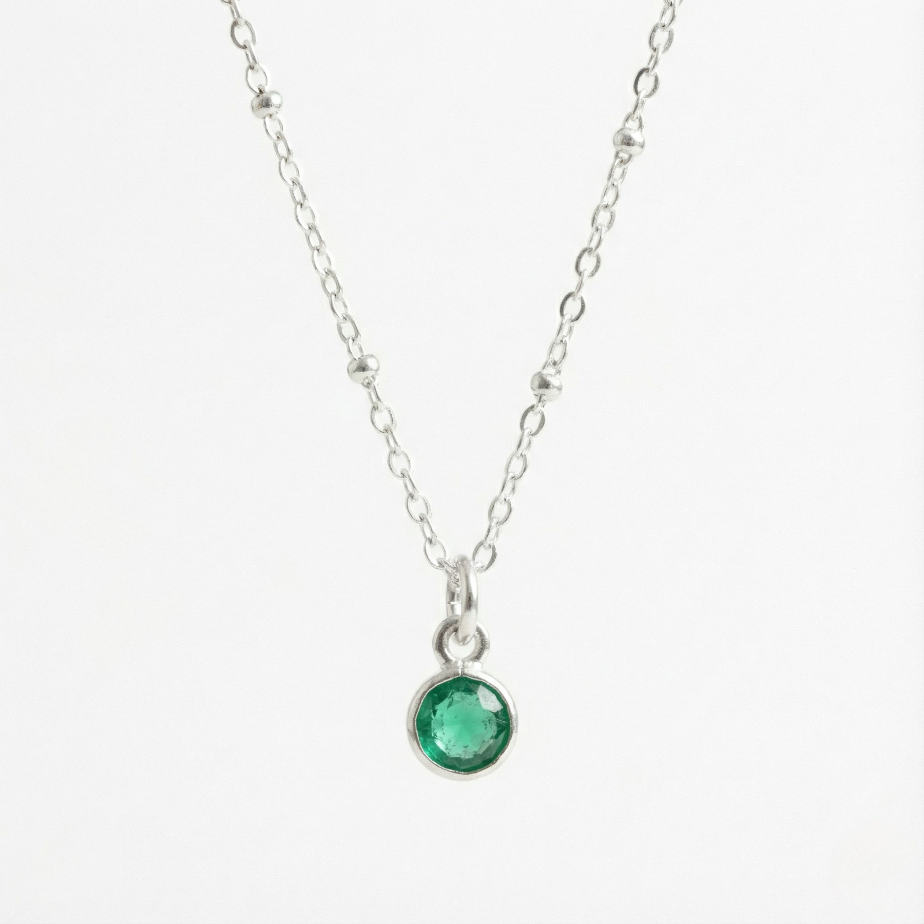 May birthstone emerald charm necklace featuring a deep green gemstone on a sterling silver chain.