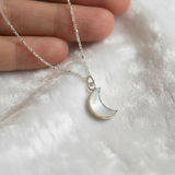 Moonstone moon-shaped pendant necklace with iridescent gemstone on a sterling silver chain.