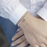 Sterling silver peridot charm bracelet worn on wrist with white cuff shirt