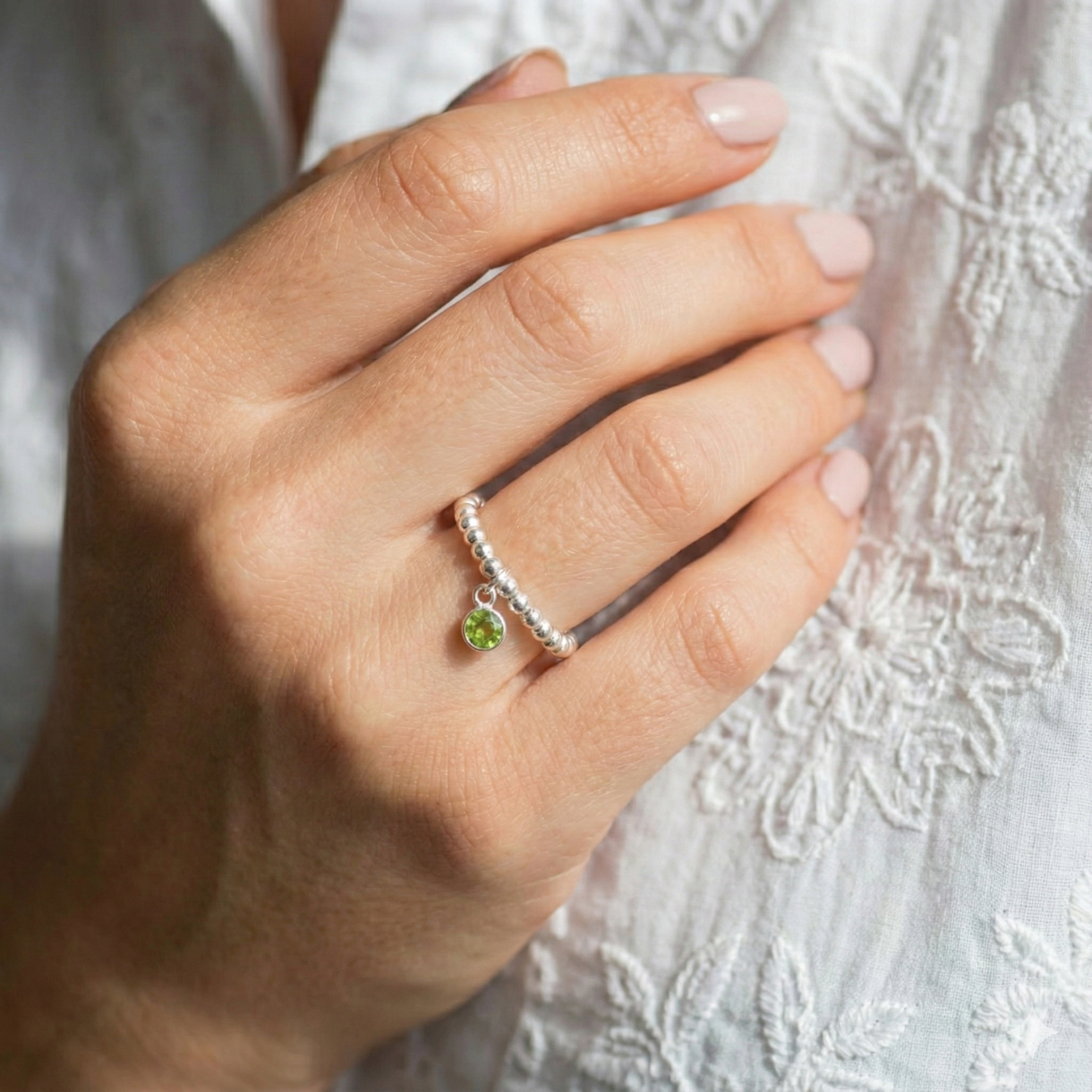 Peridot August birthstone ring with green gemstone charm on a sterling silver bead ring.