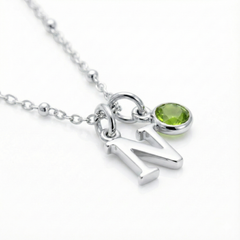Personalised initial and peridot August birthstone necklace with green gemstone charm.