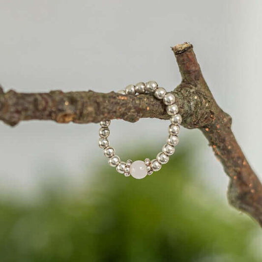 Rose Quartz Gemstone Ring with sterling silver beads and daisy spacers displayed on a branch