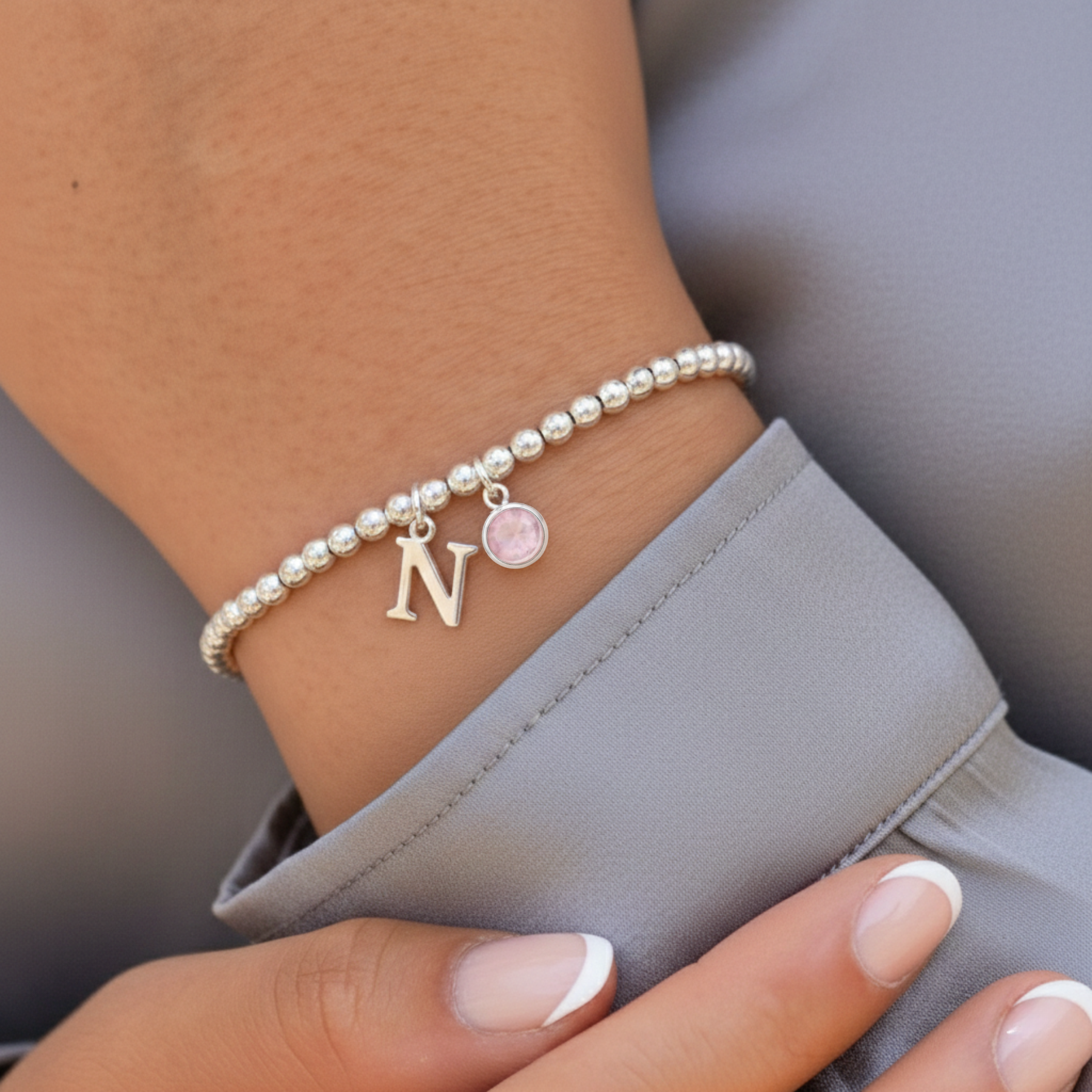 Rose quartz October birthstone bracelet with personalised initial charm in sterling silver, meaningful pink gemstone jewellery gift.