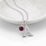 Ruby charm and initial personalised necklace in sterling silver, July birthstone jewellery gift symbolising love and strength.