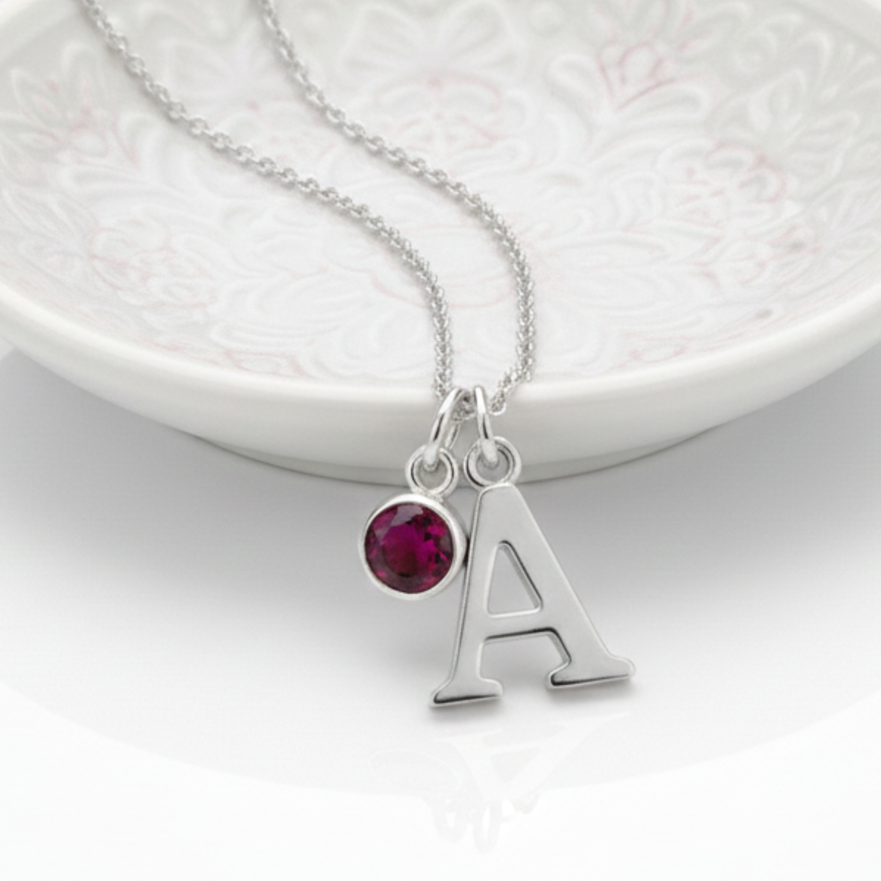 Ruby charm and initial personalised necklace in sterling silver, July birthstone jewellery gift symbolising love and strength.