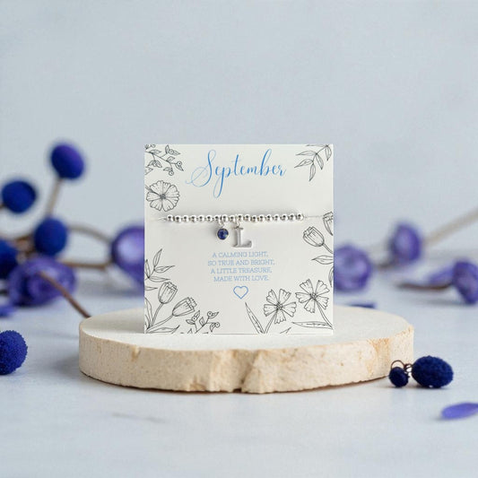 Made Here With Love September birthstone initial bracelet with sapphire charm and personalised silver letter pendant, handmade meaningful birthday jewellery gift UK.