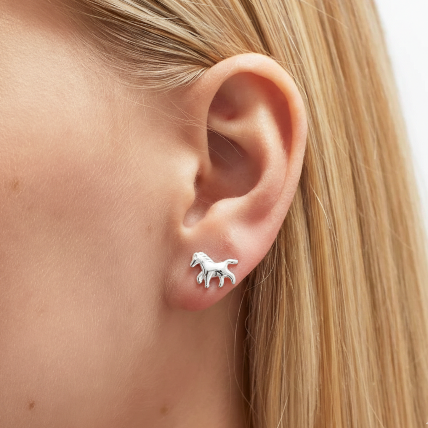 Sterling silver horse stud earrings worn on ear, subtle equestrian jewellery for everyday styling and meaningful gifting.