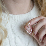 Sterling silver open heart necklace worn on chain, styled against a soft knit top.